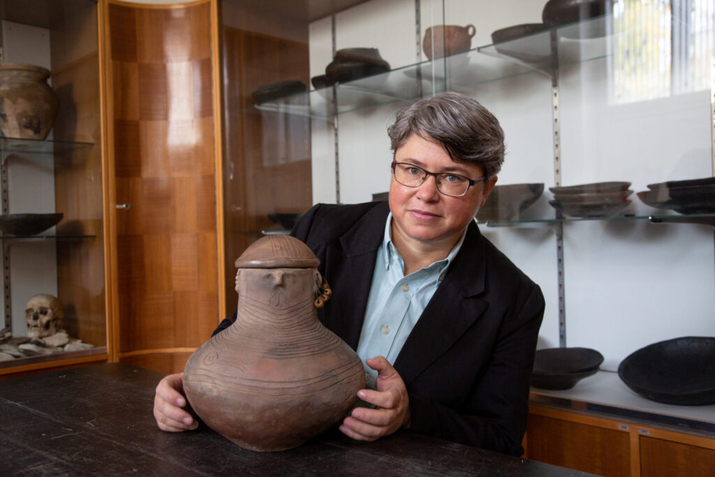 A woman holding an old clay pot.
