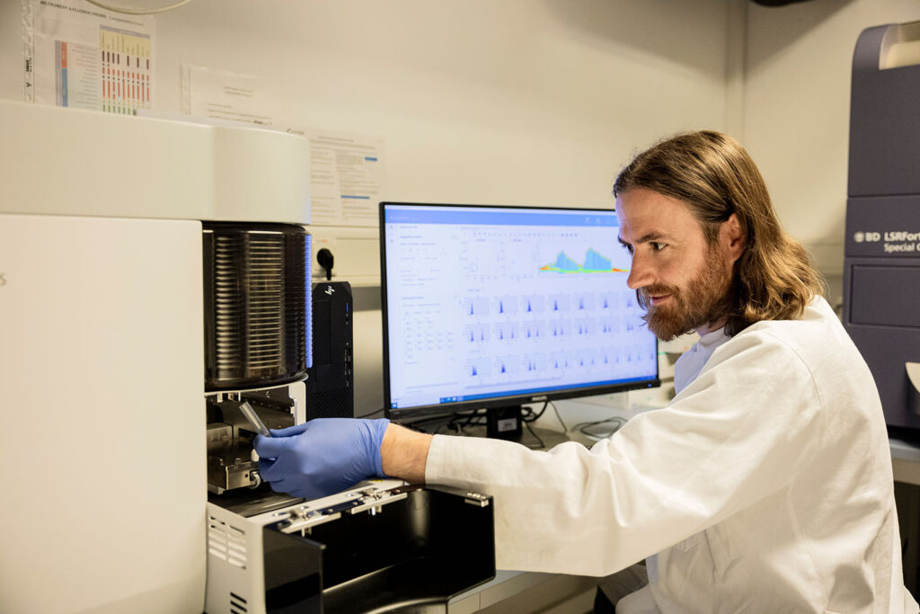 Scientist in a laboratory in front of a computer and a machine.