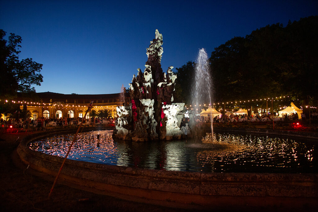 Nachtaufnahme vom FAU Schlossgartenfest mit Brunnen im Vordergrund.