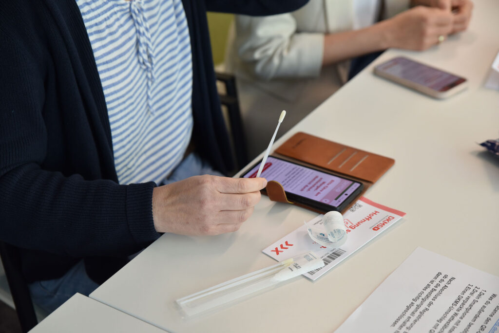 A woman holding a DKMS swab.