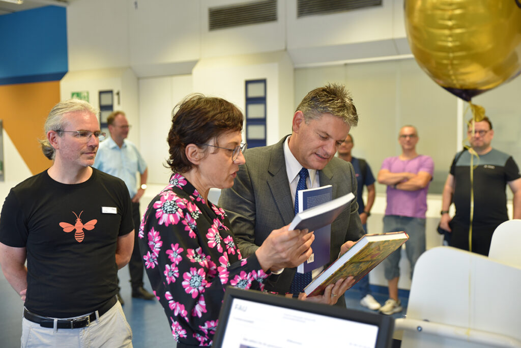 FAU-Präsident Prof. Dr. Joachim Hornegger (r.) war der ERste Kunde der sich Bücher auslieh. Bibliotheksdirektorin Konstanze Söllner und Martin Scholz (Projektleitung FOLIO-Migration) erläuterten das neue System. (Bild: FAU/Boris Mijat)