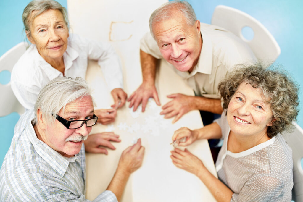 Gruppe Senioren als Freunde im Altersheim haben Spaß beim Puzzle spielen