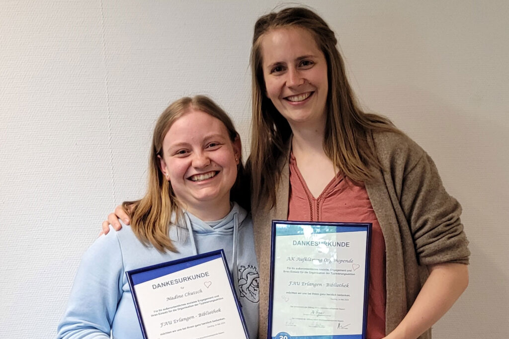 Two young women with certificates.